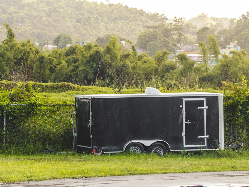 Enclosed trailer parked on the side of the road on a rainy day. 