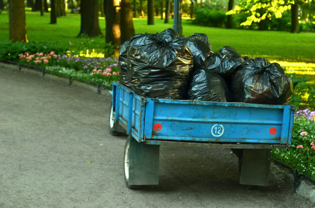 Trailer with many bags of plant garbage in the garden.Periodic garbage collection.