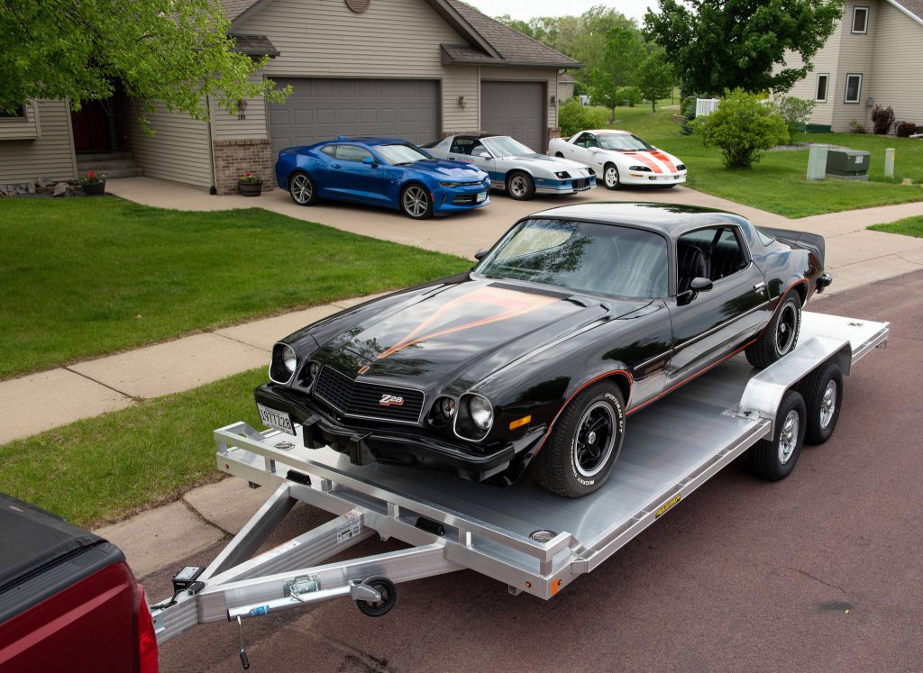 A classic, antique black car loaded onto an Aluma Trailer.