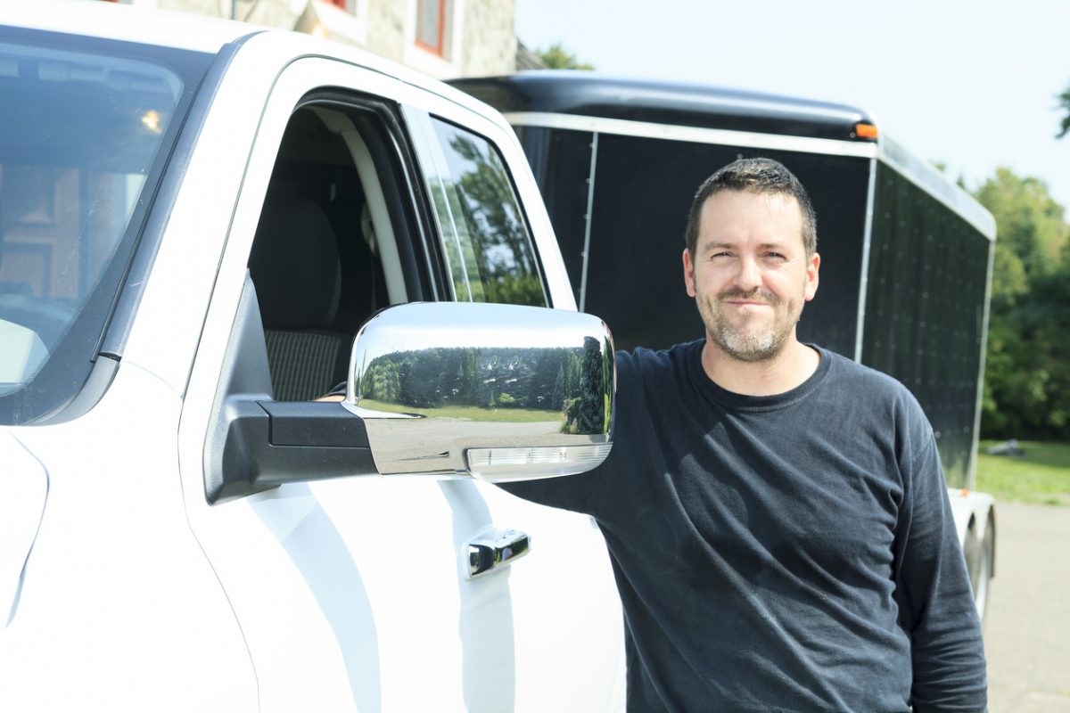 choosing a trailer for your landscape business man smiling next to truck and enclosed cargo trailer