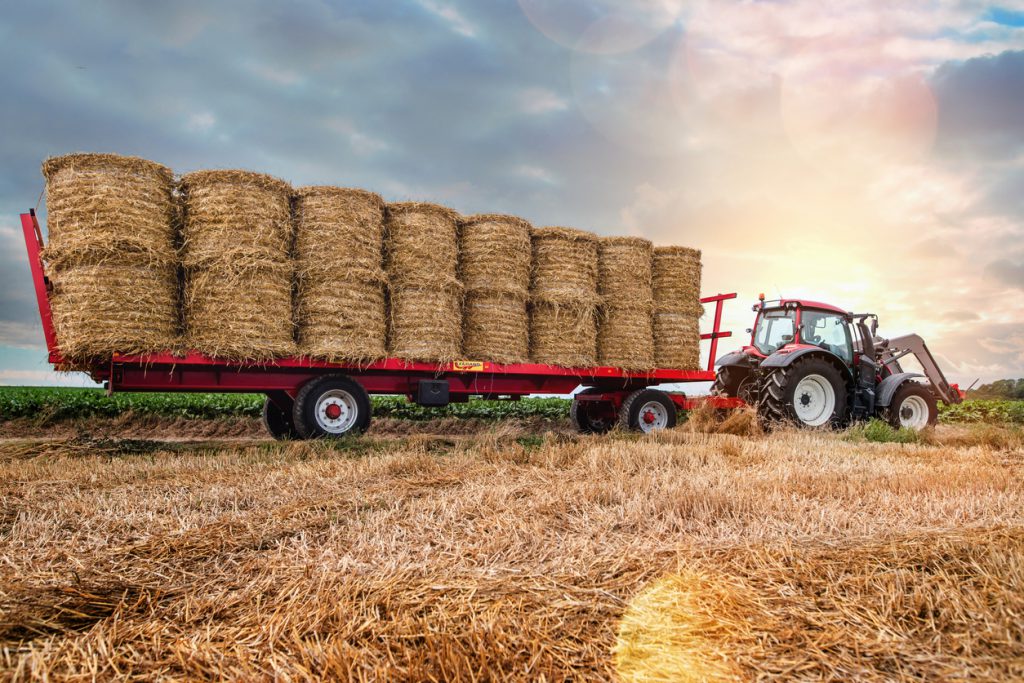 types of trailer hitches - agricultural hay trailer connected to a tractor in a field 