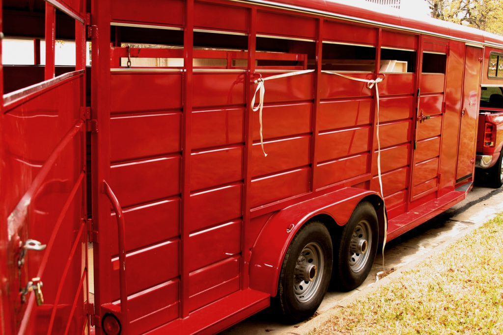 trailer tires - "Bright red trailer used to transport farm and ranch livestock.