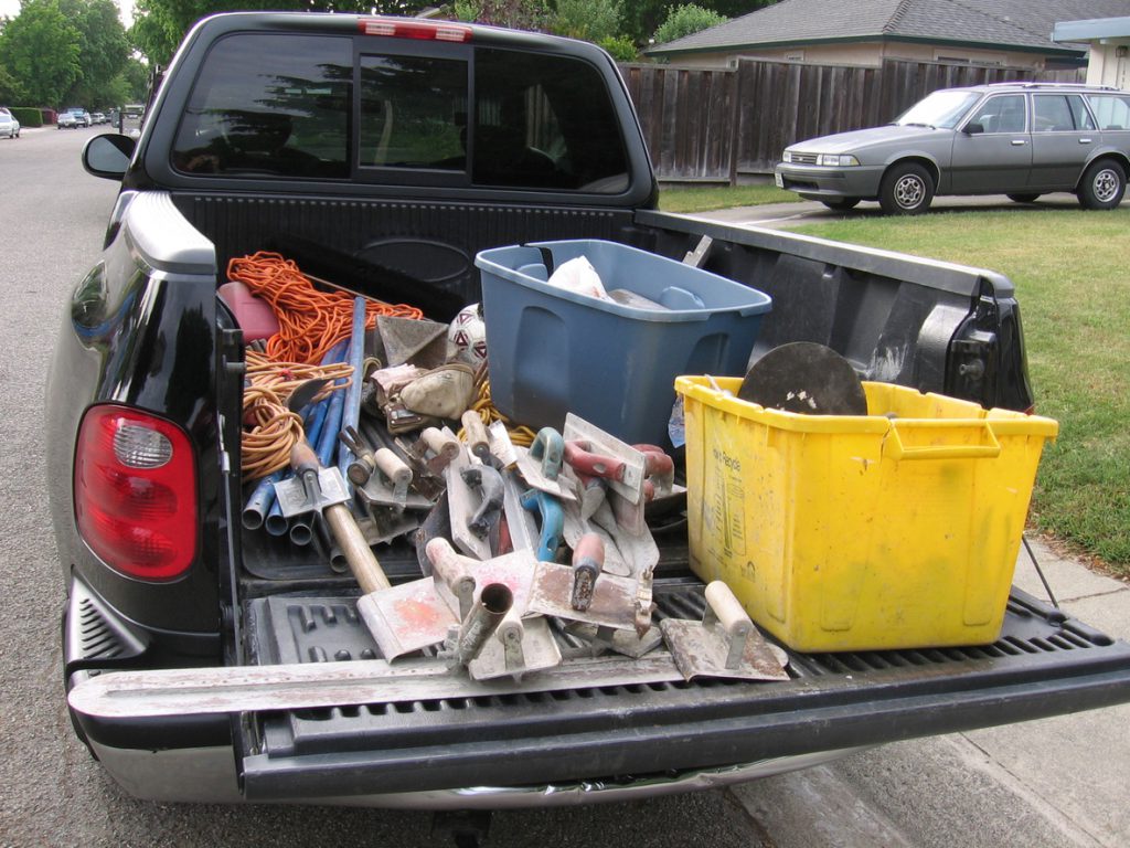 Bed of a shiny black pickup truck containing tools for working with concrete