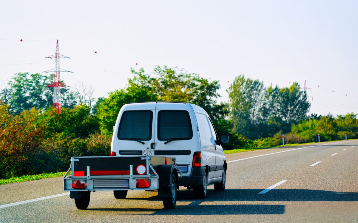 utility trailer - Car with trailer in road. Auto vehicles with Carrier transporter hauler on driveway. European transport logistics at haulage work transportation. Tow haul with driver on highway.