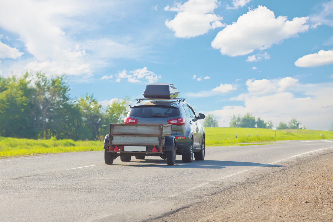 SUV with used utility trailers goes on country highway