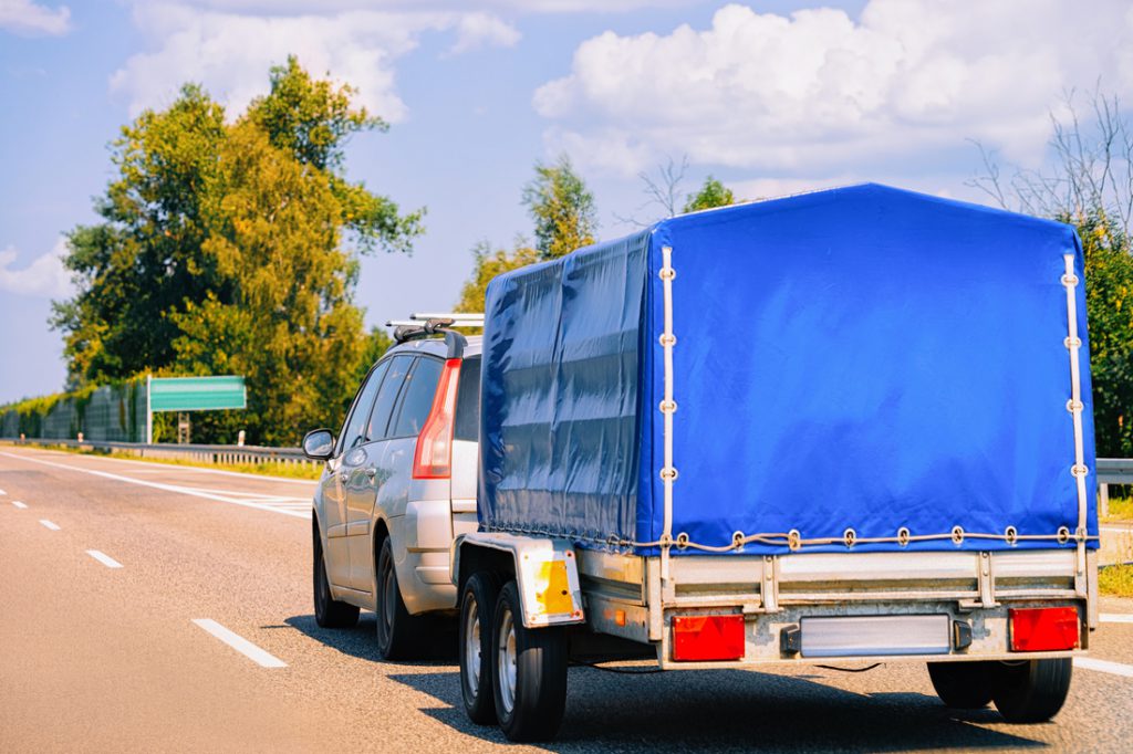 Car with covered tarp on used utility trailers in the roadway in Poland.