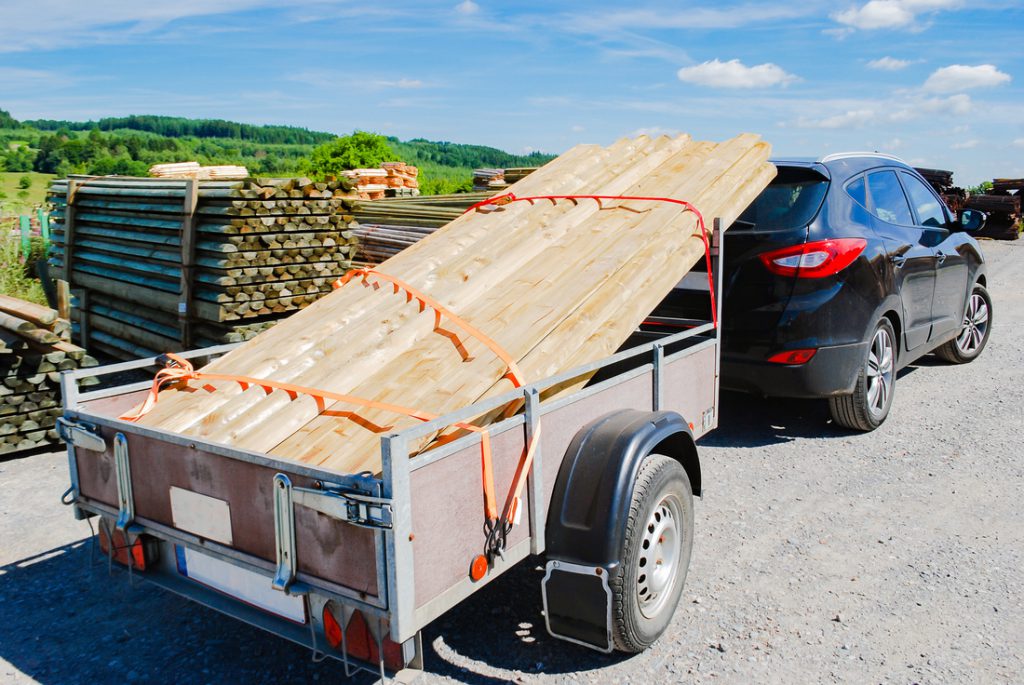 Outdoor stacking the logs on utility trailer for transport at sa