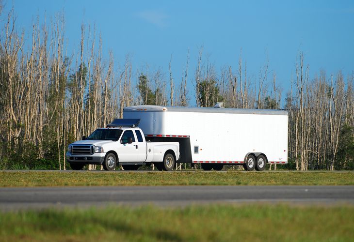 Enclosed cargo trailer that hitches in a truck bed. Possibly a gooseneck trailer hitch. 