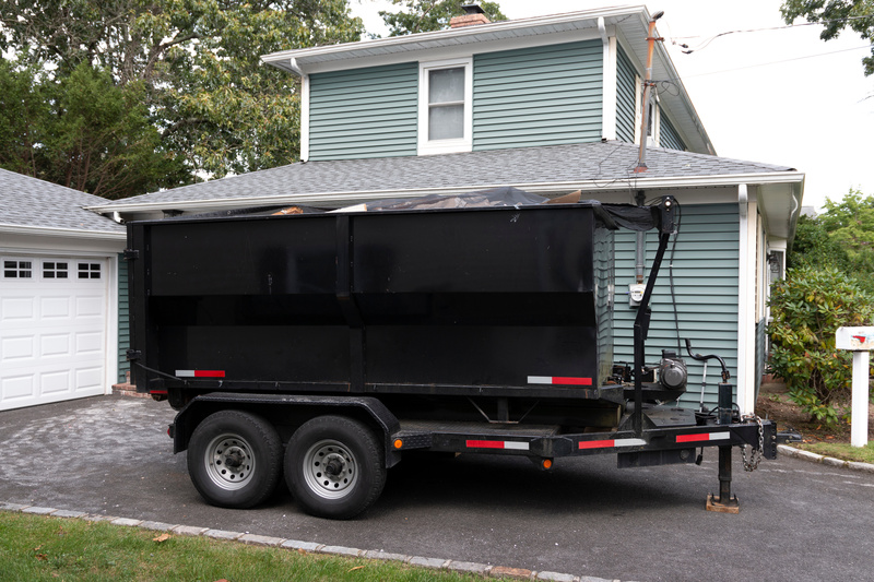 A dump trailer is parked in a driveway. 