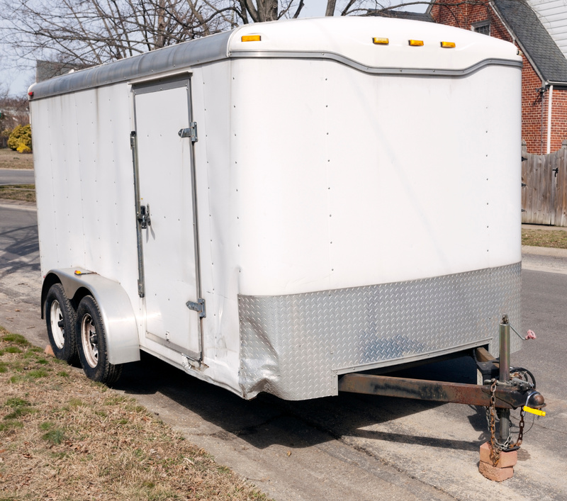 An enclosed trailer parked on the side of the road. 