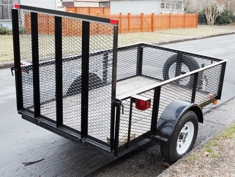 An empty utility trailer parked on the side of the road. 