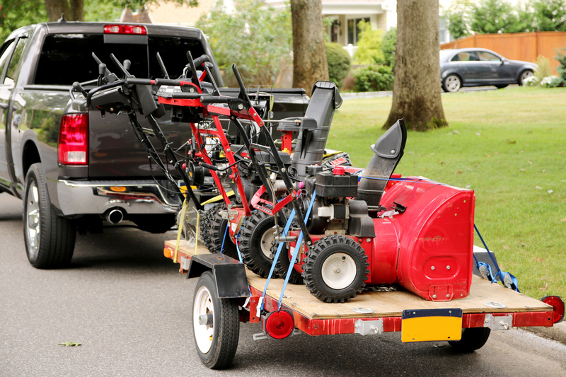 A truck hitched to an equipment trailer with snowblowers. 