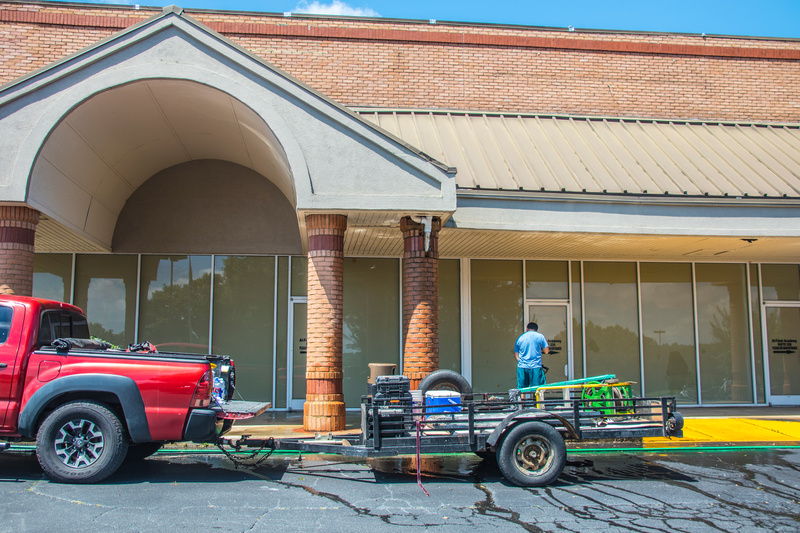 Gwinnett County, GA. A man stands in his trailer while pressure washing a walk way.