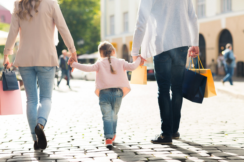 A couple and their young daughter hold hands while shopping. 