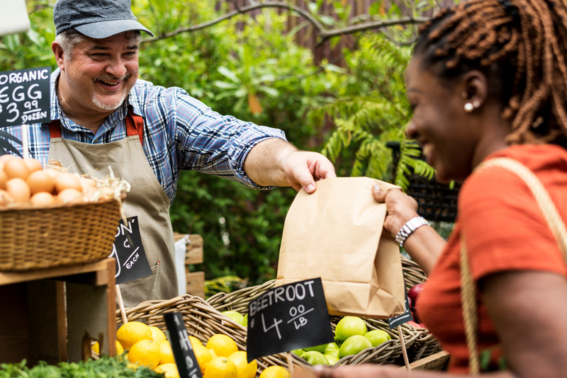 A woman purchases produce at a local farmer's market. 