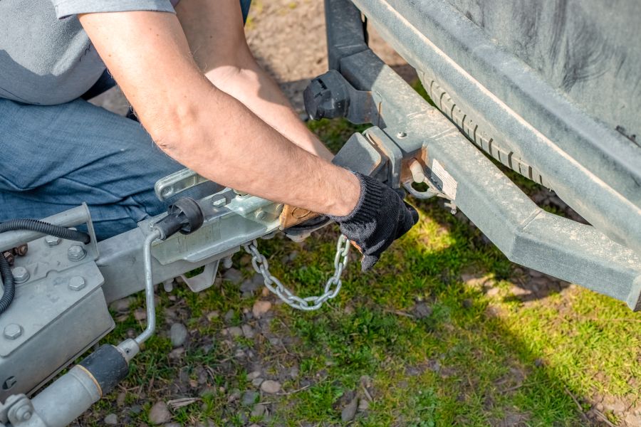 Inpsecting trailer hitch chains A man checks trailer safety chains on trailer hitch