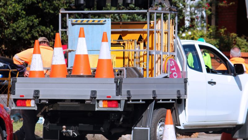 Truck with an aftermarket flatbed loaded with traffic cones and road signs for a road work company. 