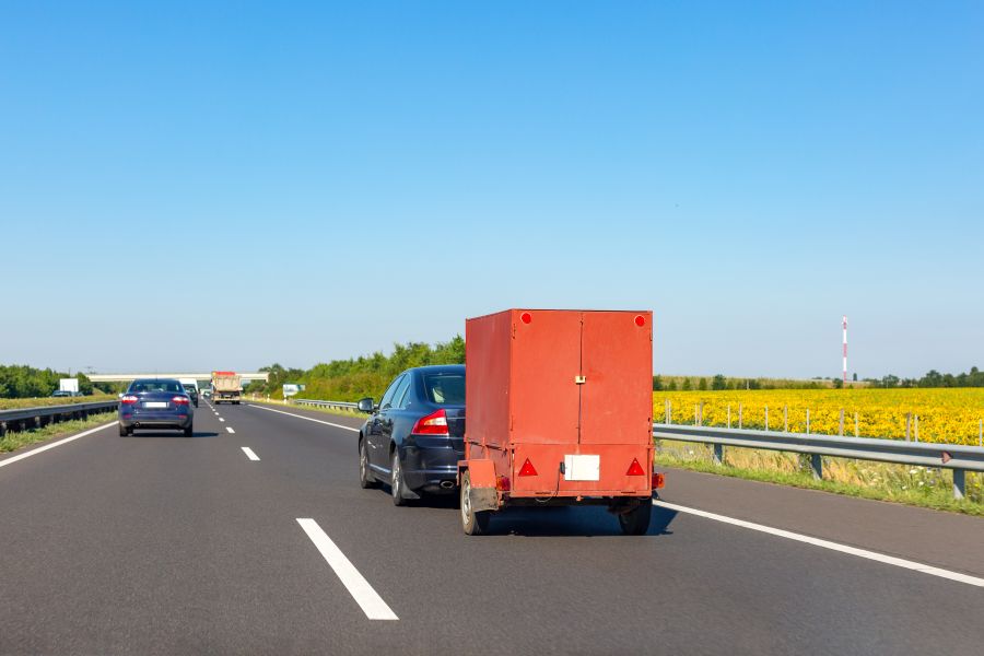 A red cargo trailer being pulled behind a truck 